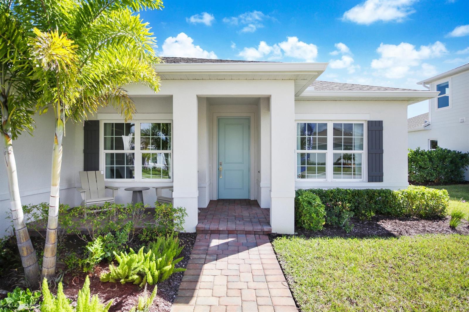 The exterior of a white house features a light blue front door and brick walkway — 56 Judah Lane, Sebastian FL 32958, SEBASTIAN, FL