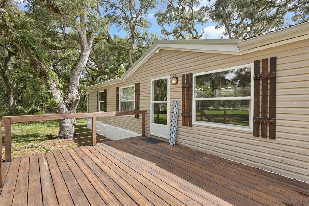 A wooden deck with a cable railing sits in front of a tan mobile home — 11 NE 434TH STREET, OLD TOWN, FL