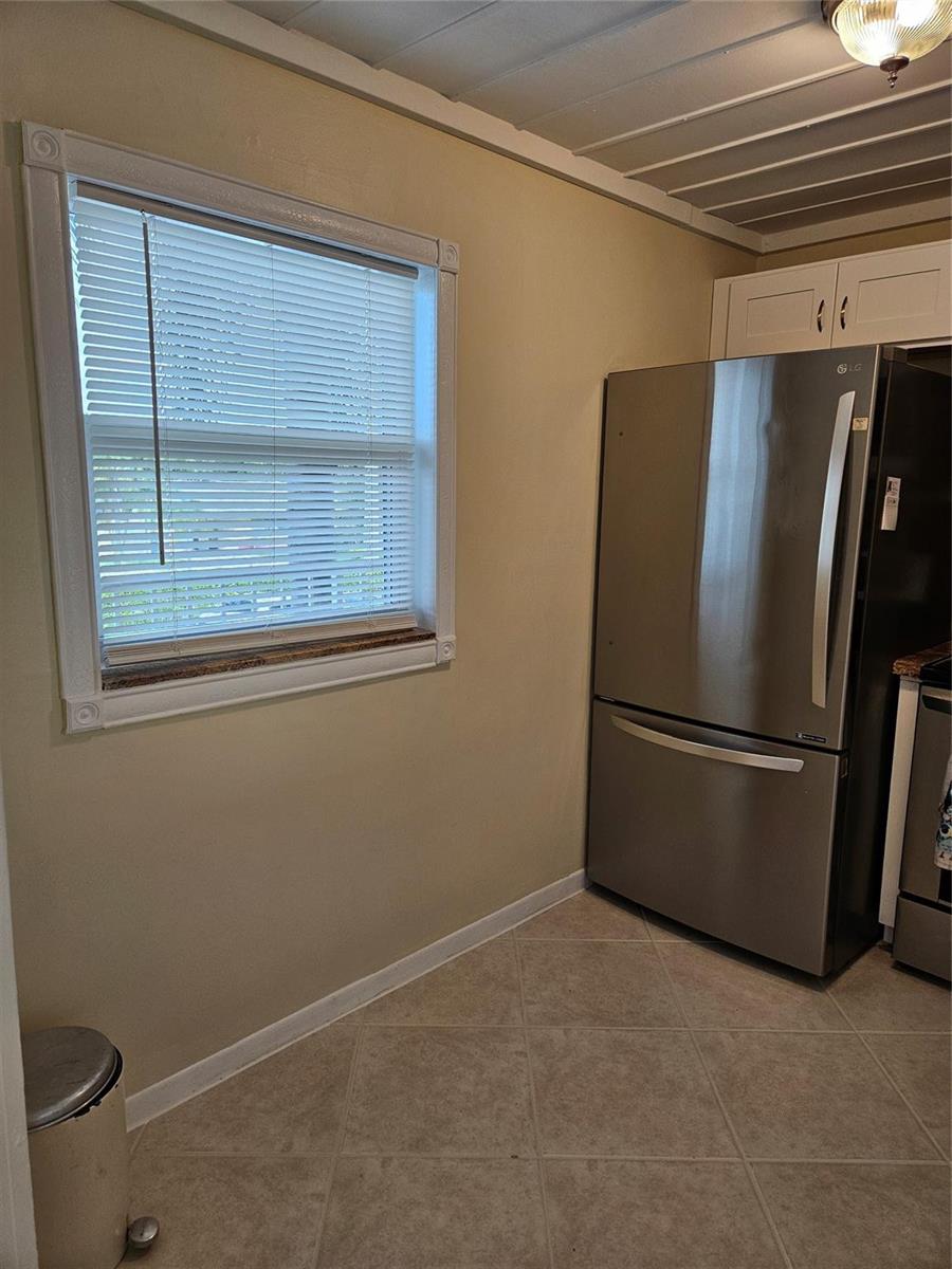 A kitchen features a stainless steel refrigerator, a window with blinds, and tiled flooring — 300 NE 26th Avenue, Boynton Beach FL 33435, BOYNTON BEACH, FL