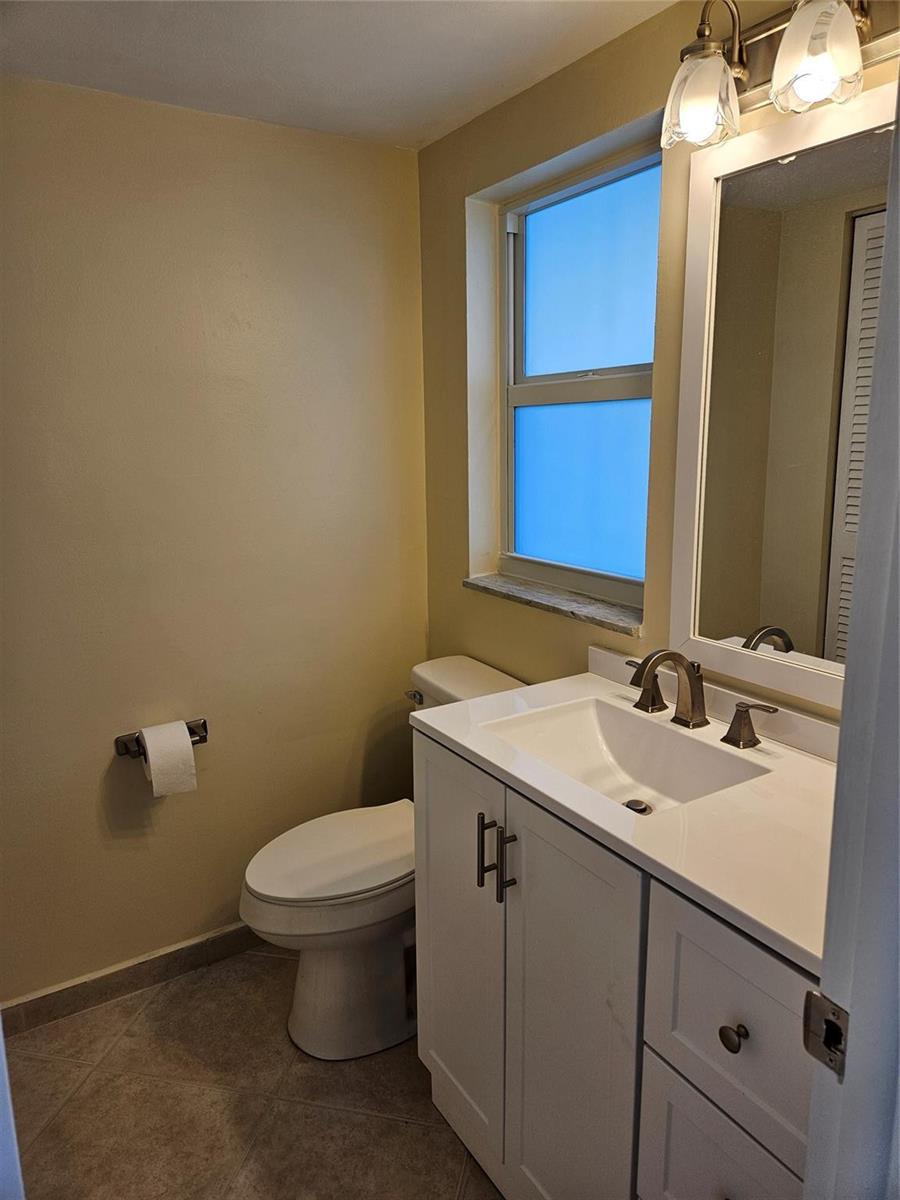 A bathroom features a white vanity with a sink, a toilet, and a window — 300 NE 26th Avenue, Boynton Beach FL 33435, BOYNTON BEACH, FL