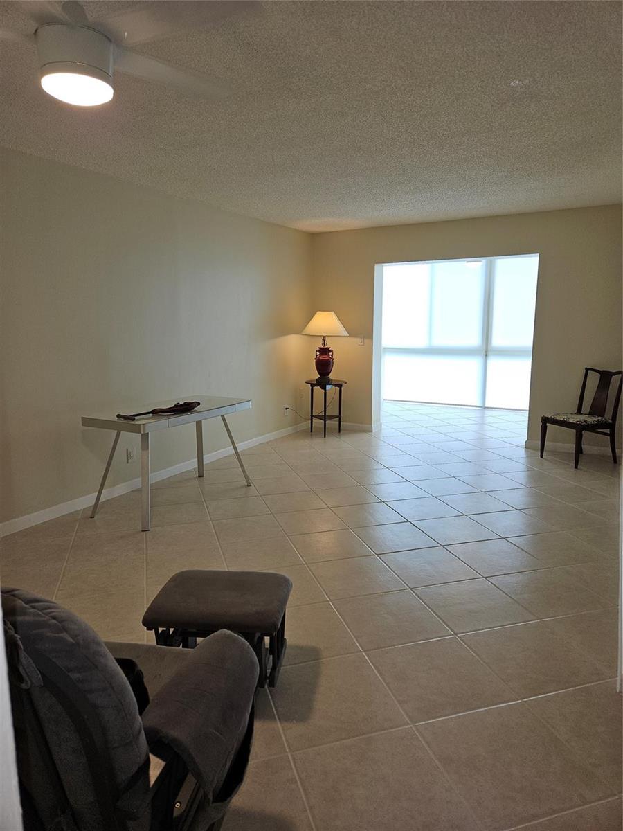 A living area with tile flooring, a desk, a chair, and a large window — 300 NE 26th Avenue, Boynton Beach FL 33435, BOYNTON BEACH, FL