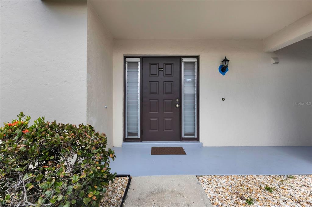 A brown front door with side windows is centered under a covered entryway — 311 GARVIN STREET UNIT 205A, PUNTA GORDA, FL
