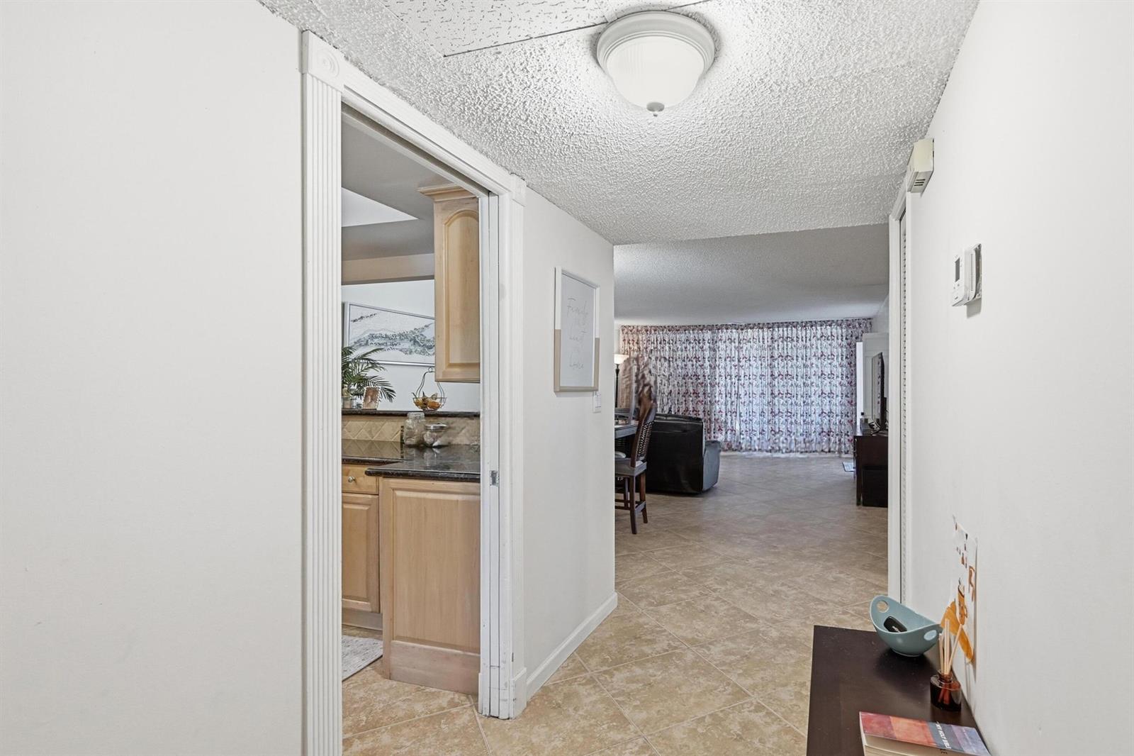 A hallway leads to a kitchen on the left and a living area beyond — 2601 S Course Drive # 202, Pompano Beach FL 33069, POMPANO BEACH, FL