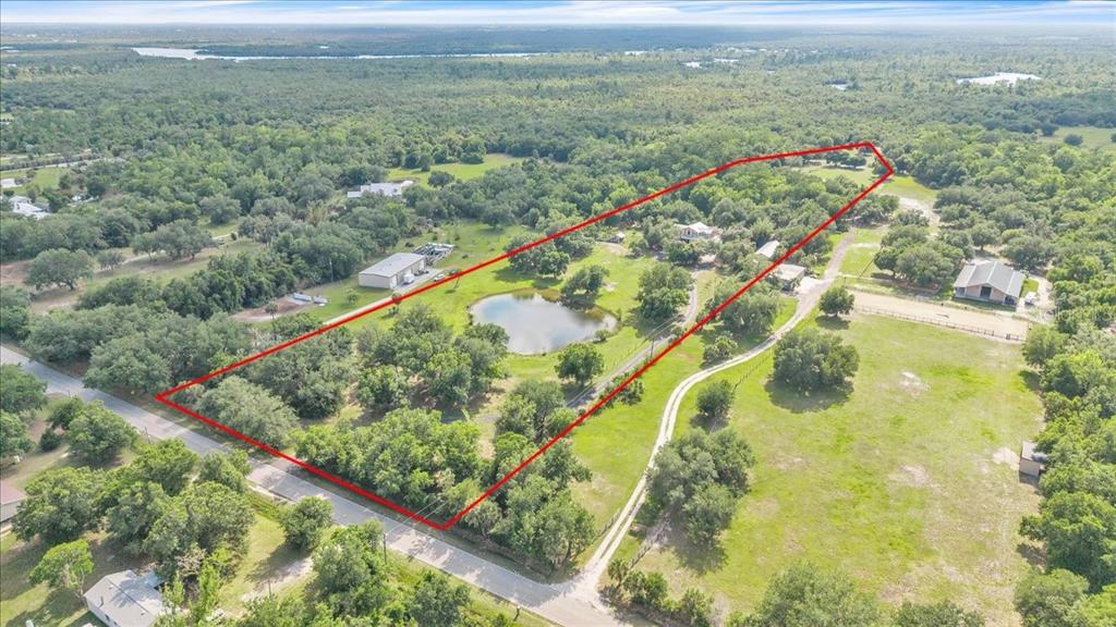 An aerial view shows a rural property with a pond, trees, and several buildings — 10597 SW KISSIMMEE ROAD, ARCADIA, FL
