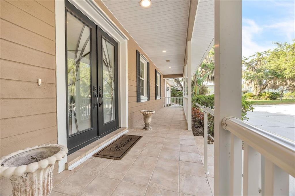 A covered porch features a tiled floor, double glass doors, and white railings — 10597 SW KISSIMMEE ROAD, ARCADIA, FL