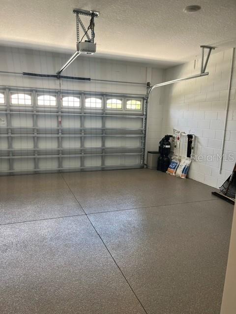 A garage features a paneled door, a ceiling-mounted opener, and a speckled epoxy floor — 7285 SW 86TH COURT, OCALA, FL