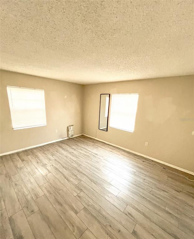 An empty room features light-colored wood-look flooring, two windows, and beige walls — 4335 AEGEAN DRIVE UNIT 108A, TAMPA, FL