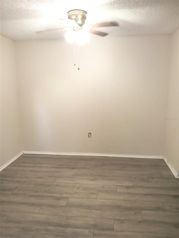 An empty room features light-colored walls, a ceiling fan, and gray wood-look flooring — 4335 AEGEAN DRIVE UNIT 108A, TAMPA, FL