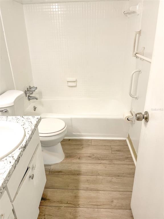 A bathroom features a white bathtub, a toilet, a vanity, and wood-look flooring — 4335 AEGEAN DRIVE UNIT 108A, TAMPA, FL