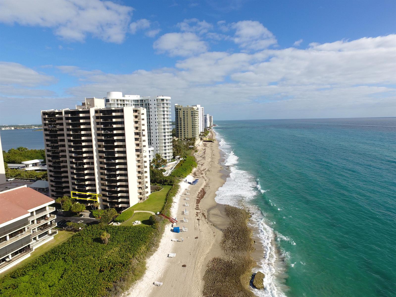 An aerial view of a high-rise condominium building situated along a sandy beach and ocean — 4200 N Ocean # 203, Singer Island FL 33404, SINGER ISLAND, FL