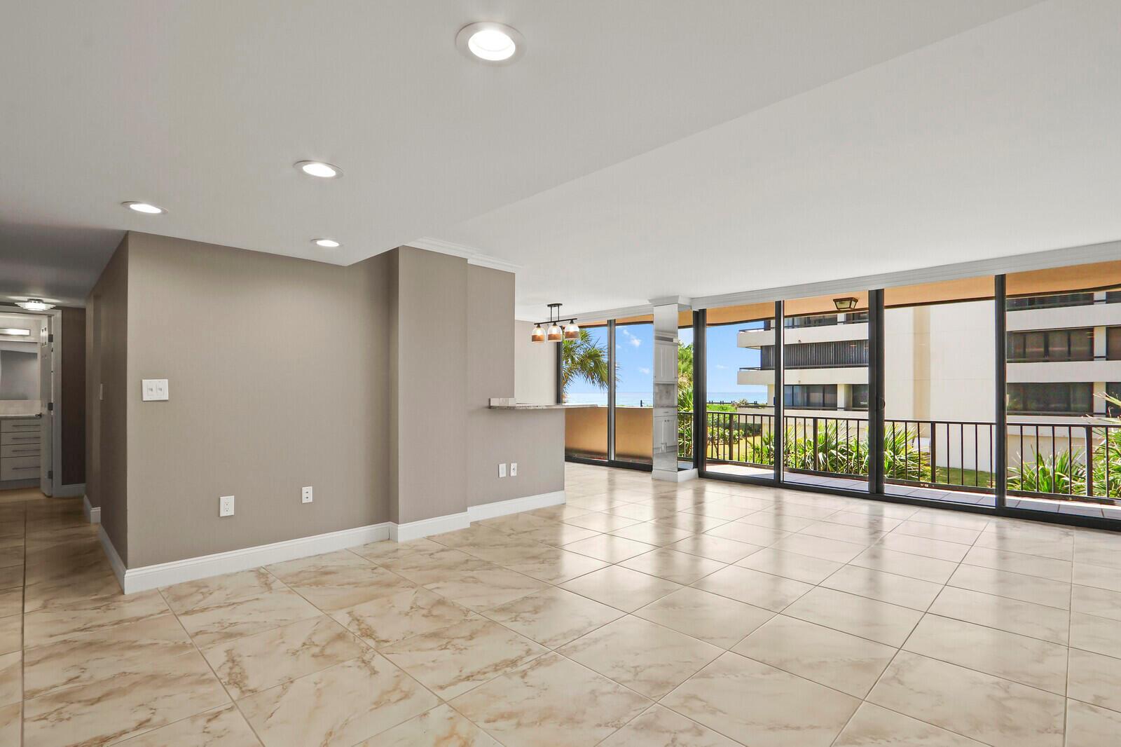 An open-concept living area features beige tile flooring, recessed lighting, and a balcony with ocean views — 4200 N Ocean # 203, Singer Island FL 33404, SINGER ISLAND, FL