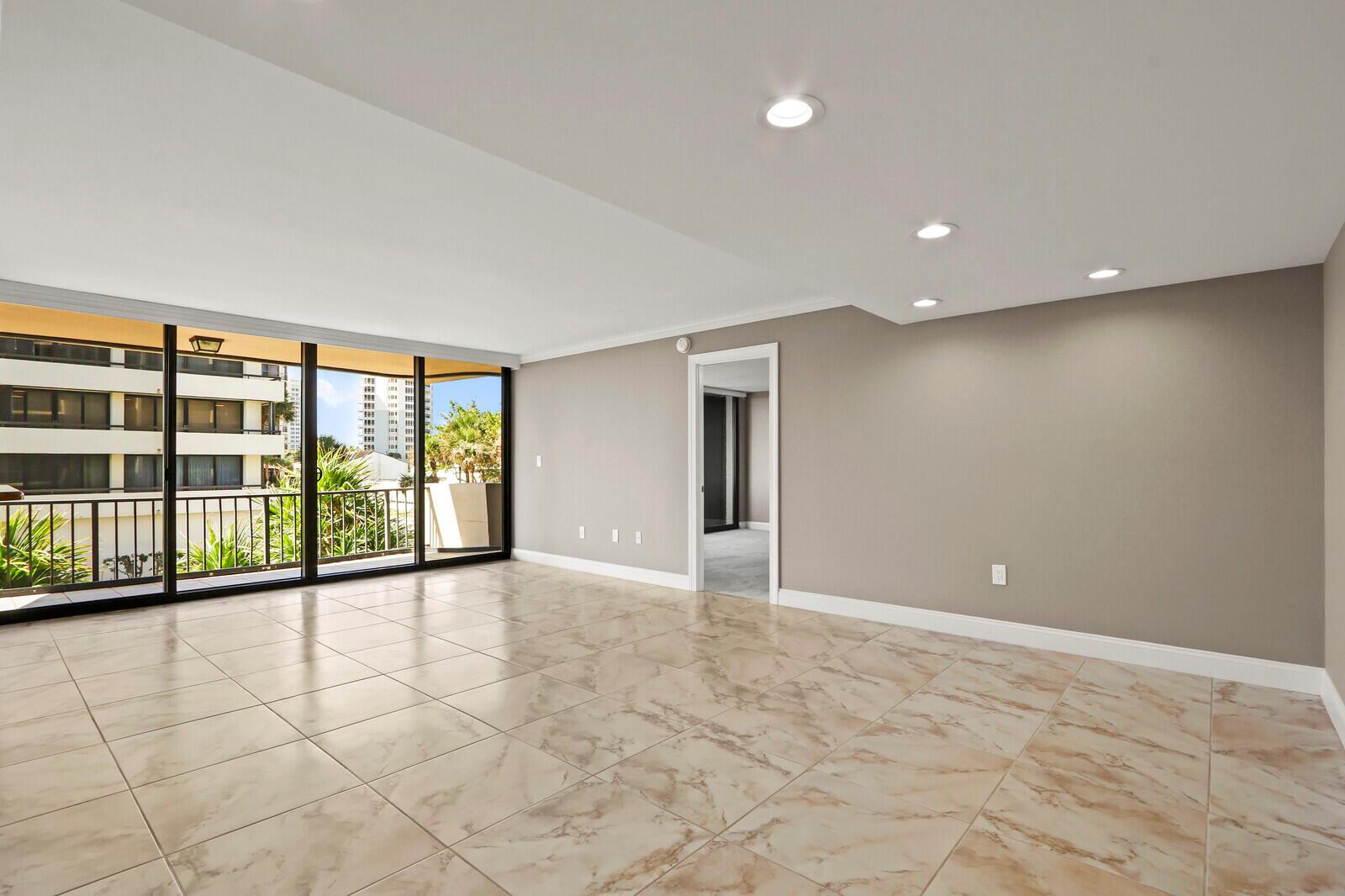 An empty room with beige marble-look tile floors, recessed lighting, and a sliding glass balcony door — 4200 N Ocean # 203, Singer Island FL 33404, SINGER ISLAND, FL
