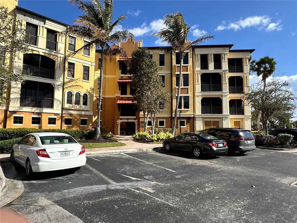 A multi-story apartment building with a parking lot and palm trees in front — 98 VIVANTE BOULEVARD UNIT 98315, PUNTA GORDA, FL