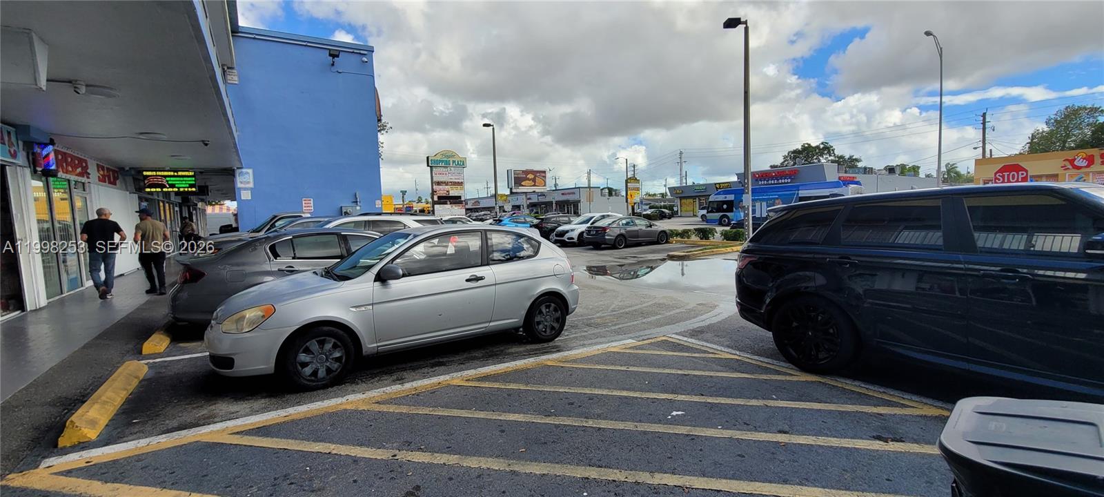 A parking lot in front of a blue commercial building with several parked cars — 5755 W Flagler St # 114, Miami FL 33144, MIAMI, FL