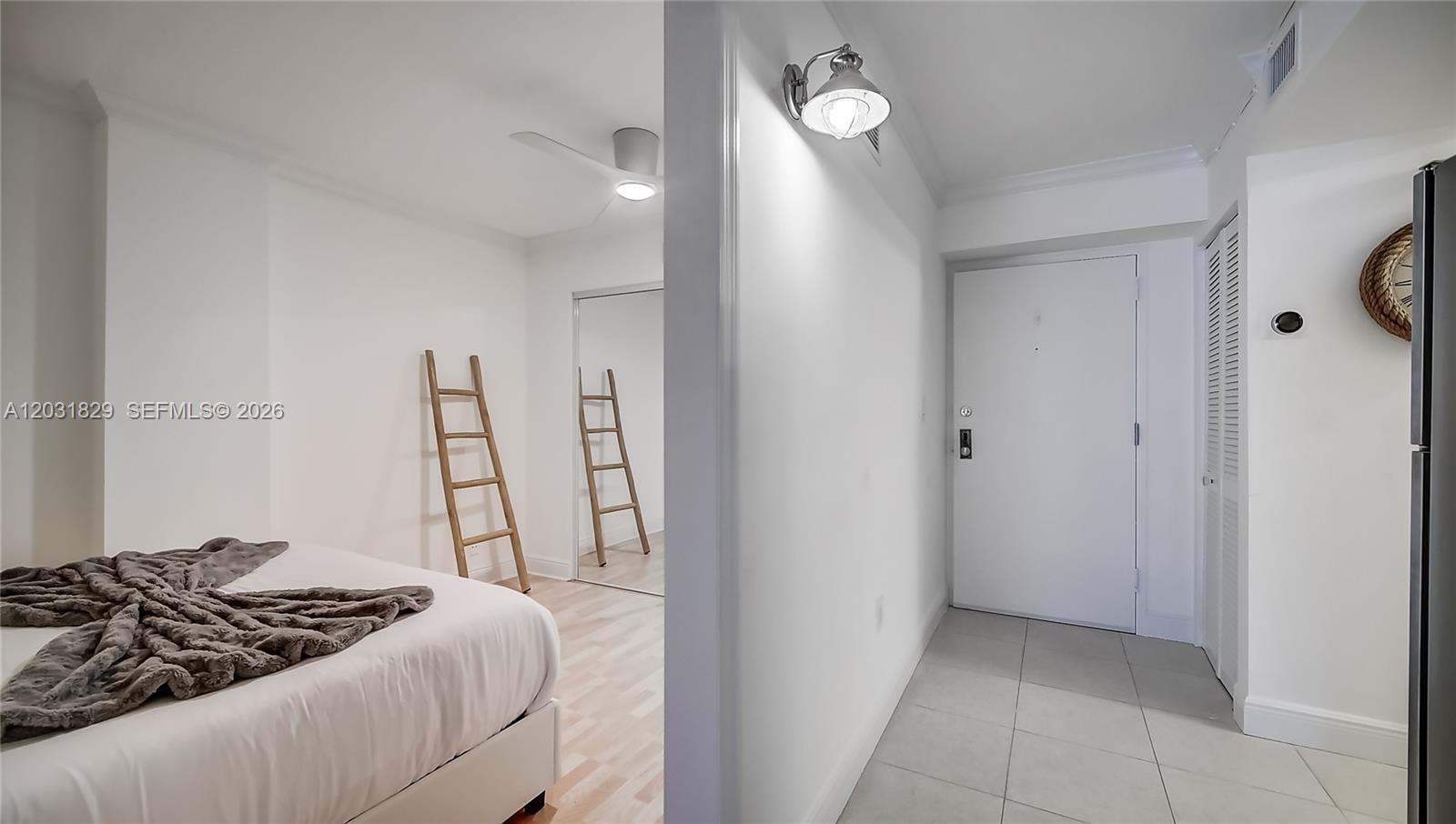 A bedroom with a wooden ladder and mirrored closet connects to a tiled entryway — 2401 Collins Ave # 904, Miami Beach FL 33140, MIAMI BEACH, FL