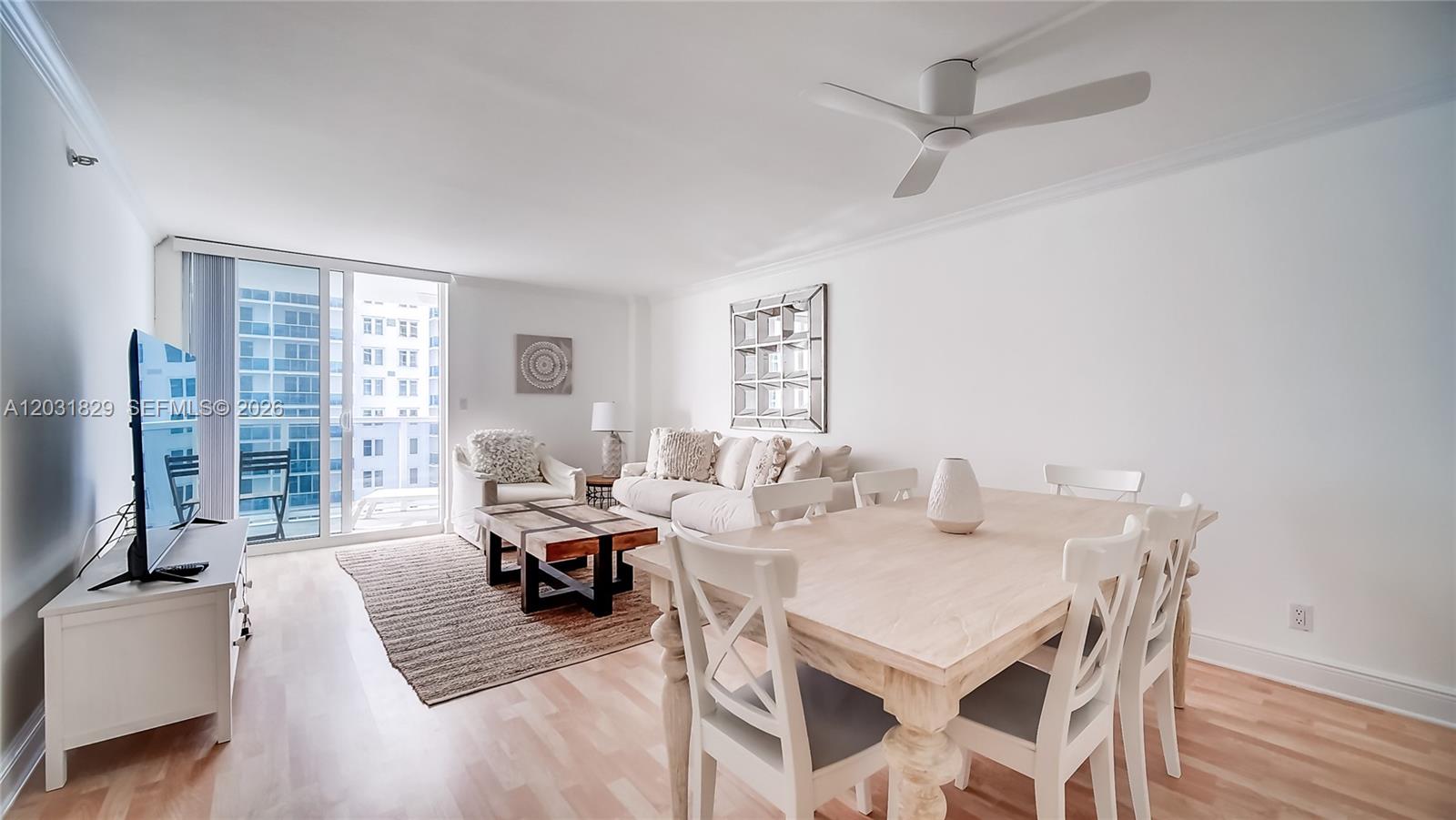 A living and dining area features light wood floors, white furniture, and a ceiling fan — 2401 Collins Ave # 904, Miami Beach FL 33140, MIAMI BEACH, FL
