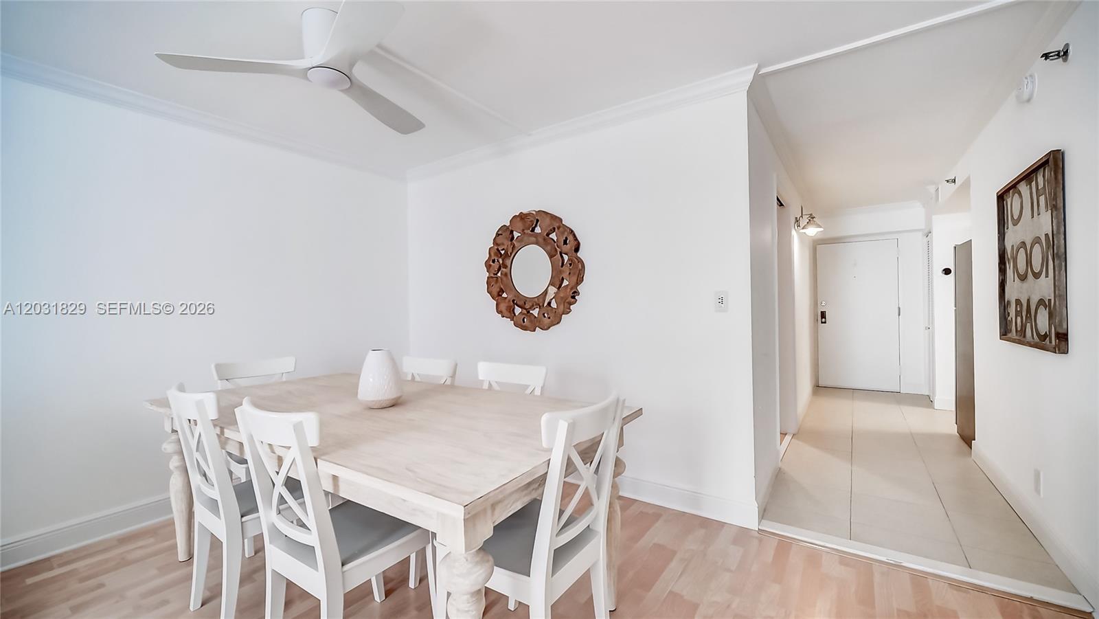 A dining room features a light wood table, white chairs, and a decorative circular mirror — 2401 Collins Ave # 904, Miami Beach FL 33140, MIAMI BEACH, FL