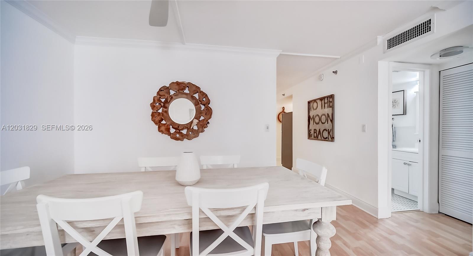 A dining area features a light wood table, white chairs, and wall-mounted decorative accents — 2401 Collins Ave # 904, Miami Beach FL 33140, MIAMI BEACH, FL