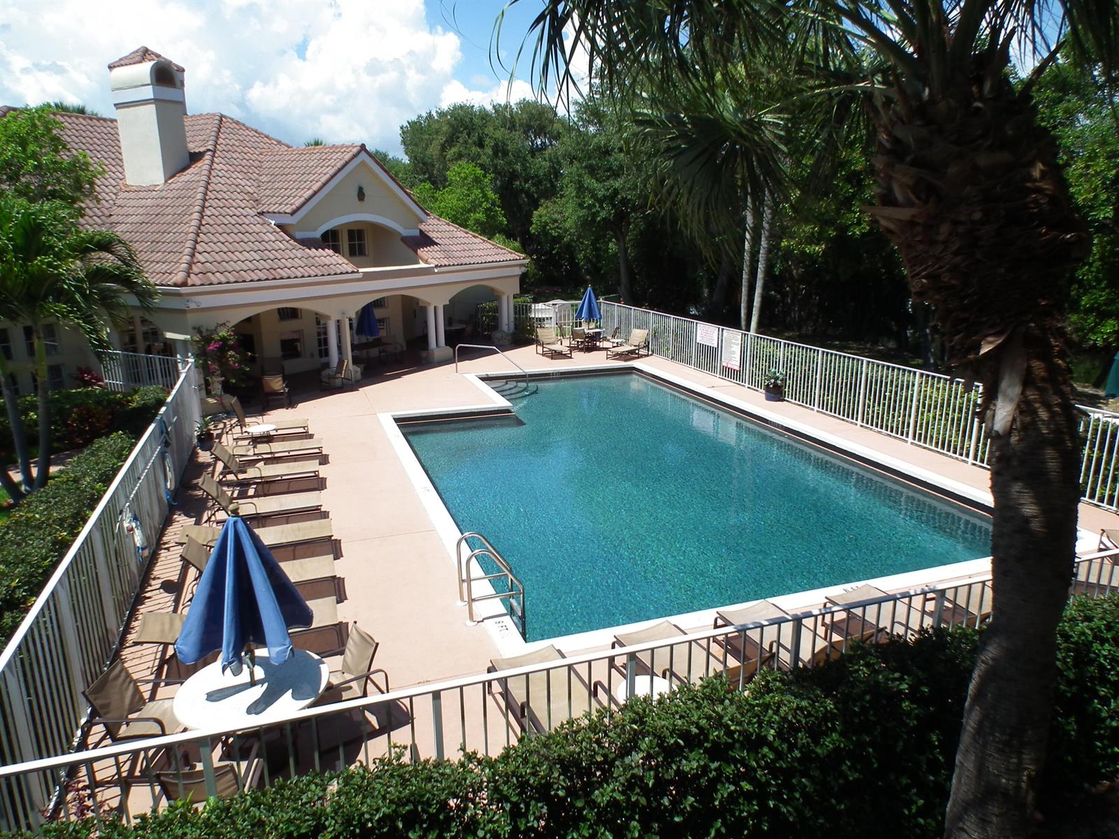 An outdoor swimming pool with lounge chairs and a patio area next to a house — 815 W Boynton Beach Boulevard # 103, Boynton Beach FL 33426, BOYNTON BEACH, FL