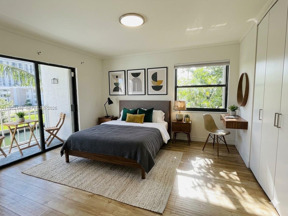 A bedroom features a bed, a desk, a balcony, and light wood flooring — 1650 NE 115th St # 311, Miami FL 33181, MIAMI, FL