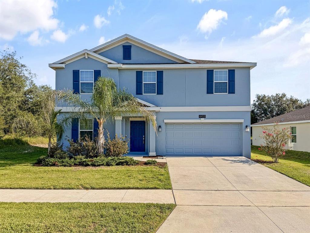 A two-story blue house with a two-car garage and a palm tree in the yard — 4459 TAHOE CIRCLE, CLERMONT, FL