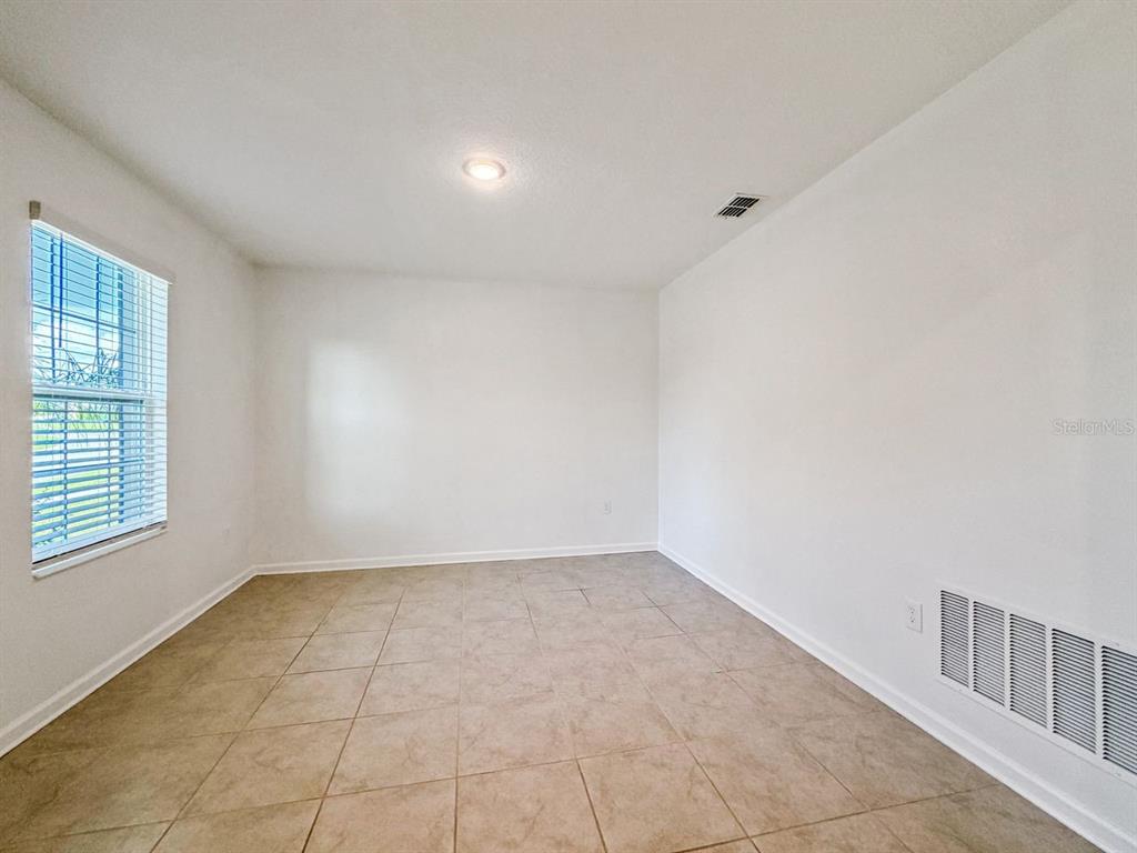 An empty room features white walls, tile flooring, a single window, and a ceiling light — 4459 TAHOE CIRCLE, CLERMONT, FL