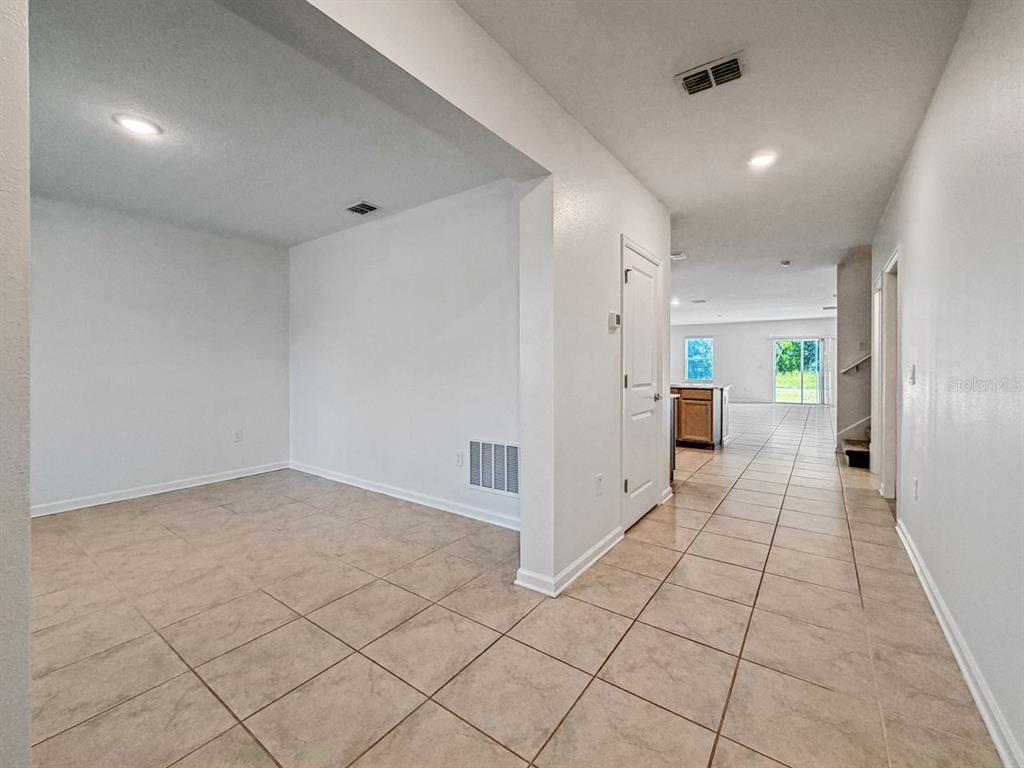 A tiled entryway leads to an open-concept kitchen and living area with white walls — 4459 TAHOE CIRCLE, CLERMONT, FL