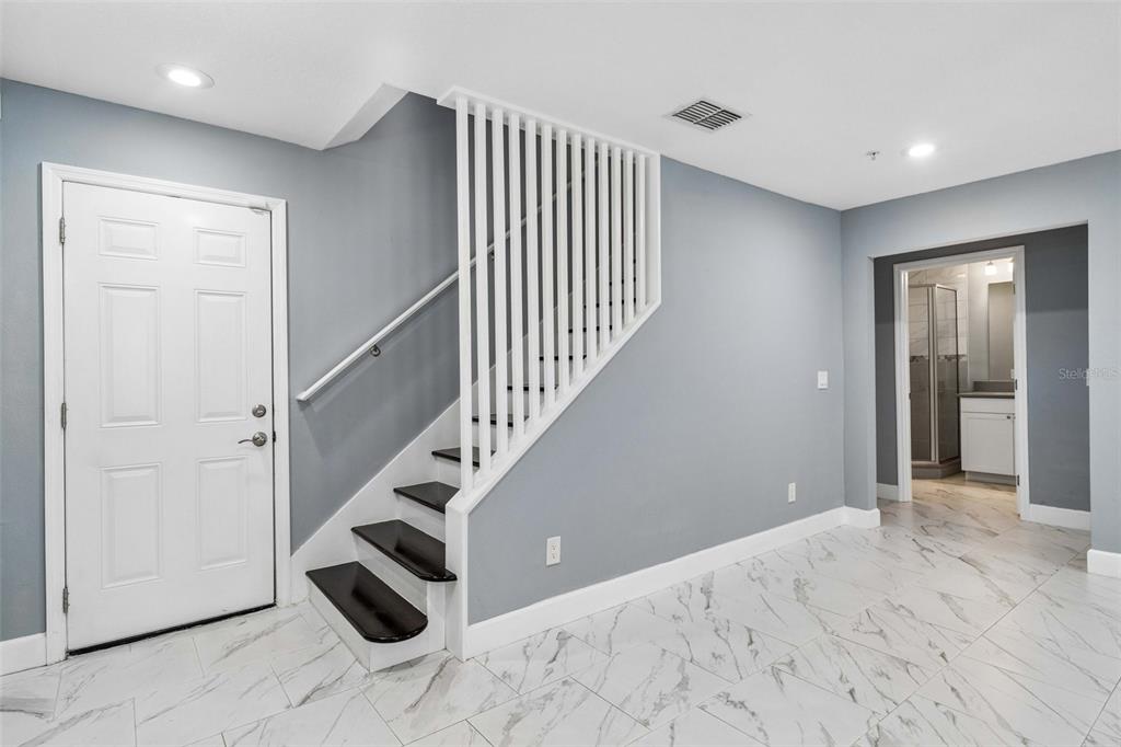 An entryway features a white door, a staircase with dark treads, and white marble flooring — 2613 ESPANA COURT, TAMPA, FL