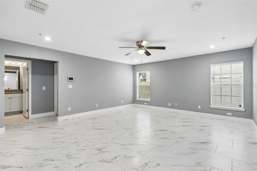 A spacious room with gray walls, white marble-look tile flooring, and a ceiling fan — 2613 ESPANA COURT, TAMPA, FL