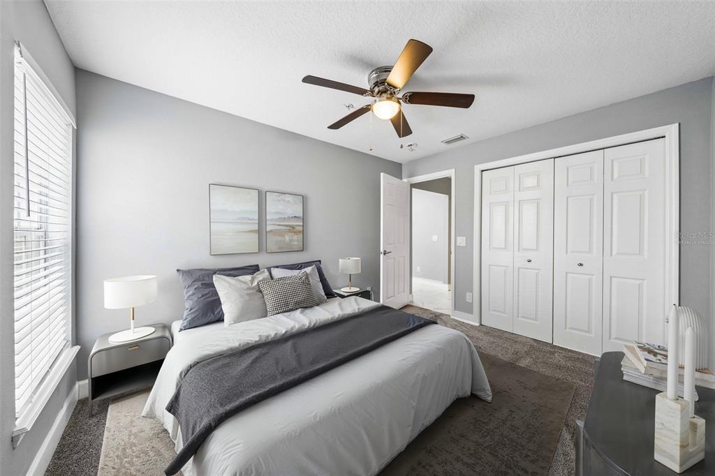 A bedroom with a bed, ceiling fan, white closet doors, and gray carpeted flooring — 2613 ESPANA COURT, TAMPA, FL