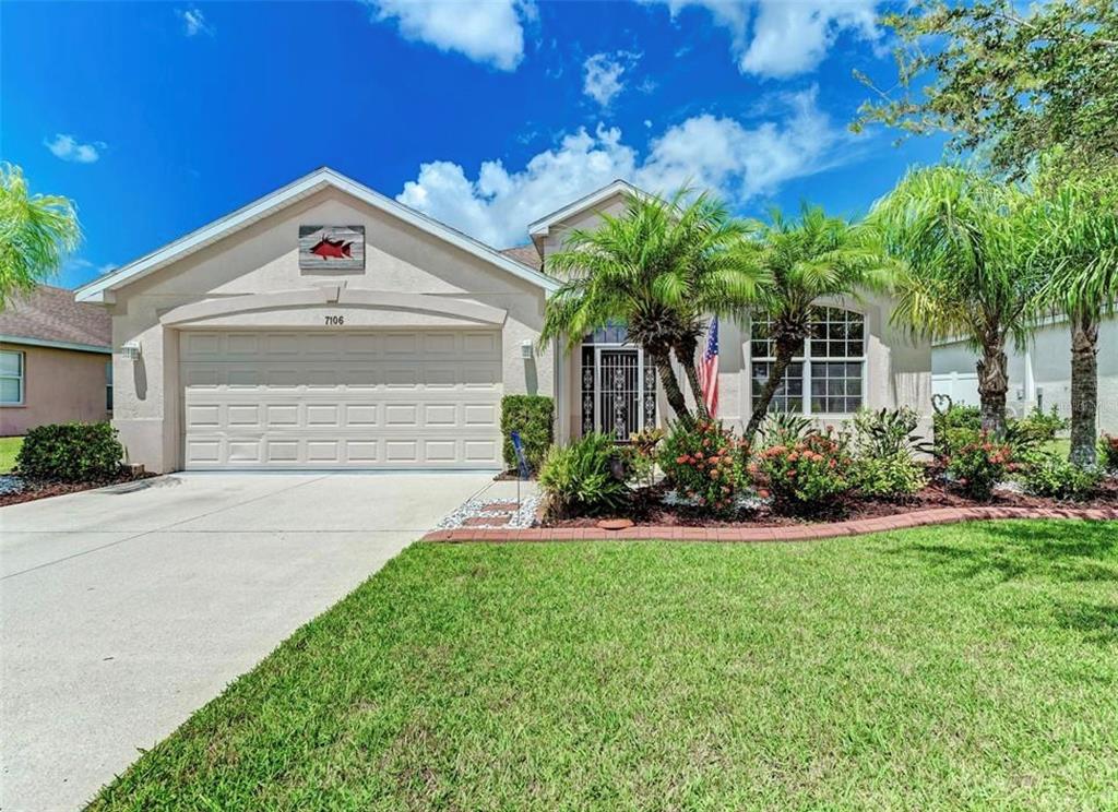 A single-story suburban house with a beige stucco exterior, two-car garage, and front landscaping — 7106 50TH AVENUE CIRCLE E, PALMETTO, FL