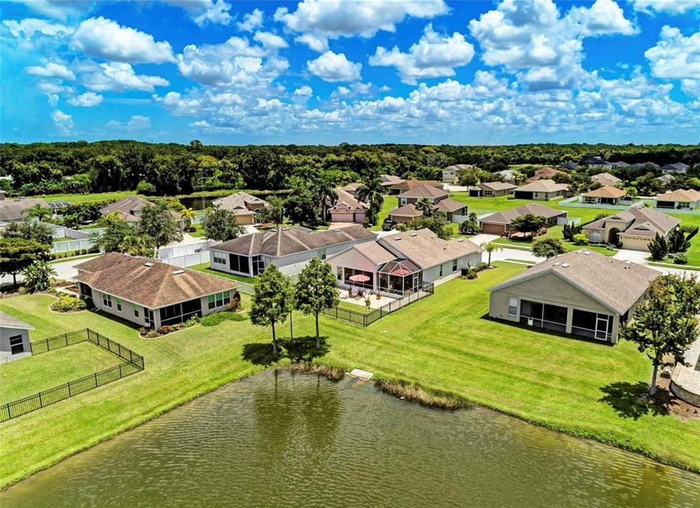An aerial view of several suburban houses with brown roofs situated around a small lake — 7106 50TH AVENUE CIRCLE E, PALMETTO, FL