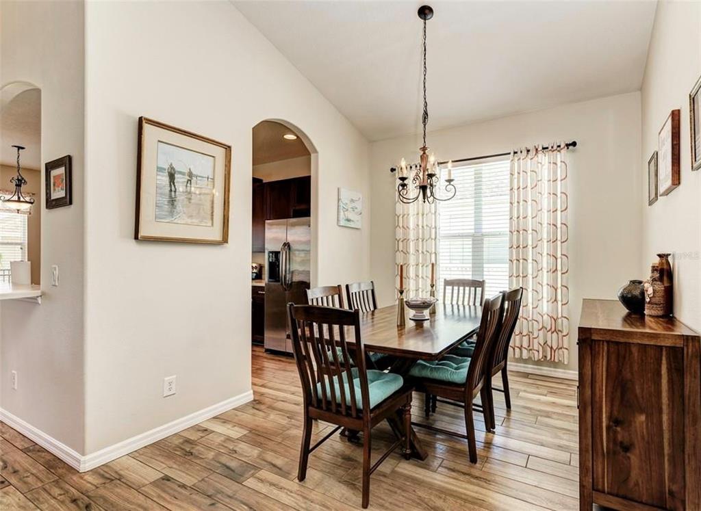 A dining room features a wooden table, chairs with teal cushions, and a chandelier — 7106 50TH AVENUE CIRCLE E, PALMETTO, FL