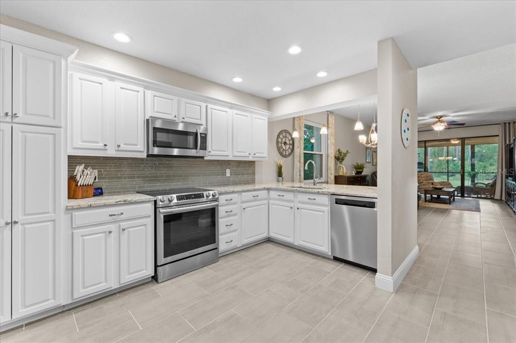 A kitchen with white cabinets, stainless steel appliances, granite countertops, and light tile flooring — 10 SHAMROCK WAY UNIT 10, OLDSMAR, FL