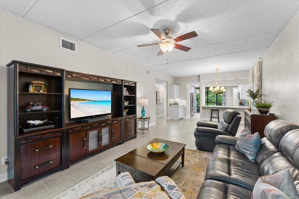 A living room features a large entertainment center, leather furniture, and tile flooring — 10 SHAMROCK WAY UNIT 10, OLDSMAR, FL