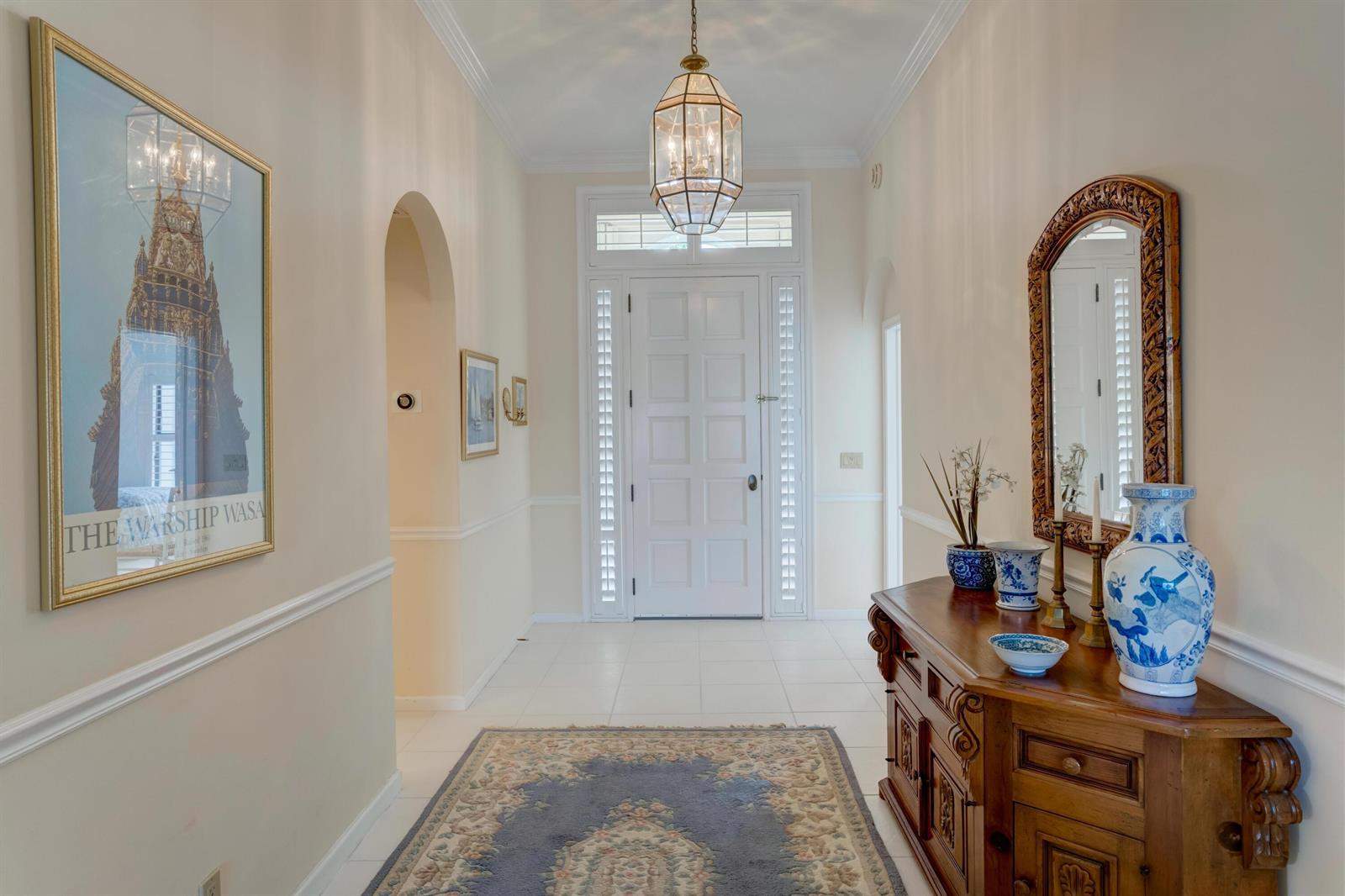 A bright foyer features a white front door, tile flooring, a wooden console, and artwork — 3518 Lantern Bay Drive, Jupiter FL 33477, JUPITER, FL