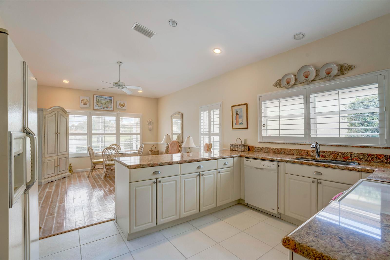 A kitchen with white cabinets, granite countertops, and a dining area with a ceiling fan — 3518 Lantern Bay Drive, Jupiter FL 33477, JUPITER, FL