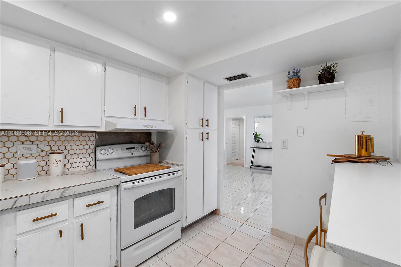 A white kitchen features a stove, tiled backsplash, and a doorway leading to another room — 6039 Collins Ave # 934, Miami Beach FL 33140, MIAMI BEACH, FL