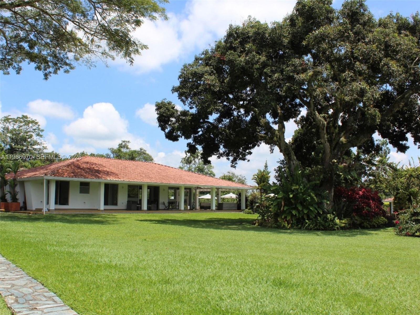 A single-story white house with a red tile roof sits on a large grassy lawn — 00 N Outside of Country, FL
