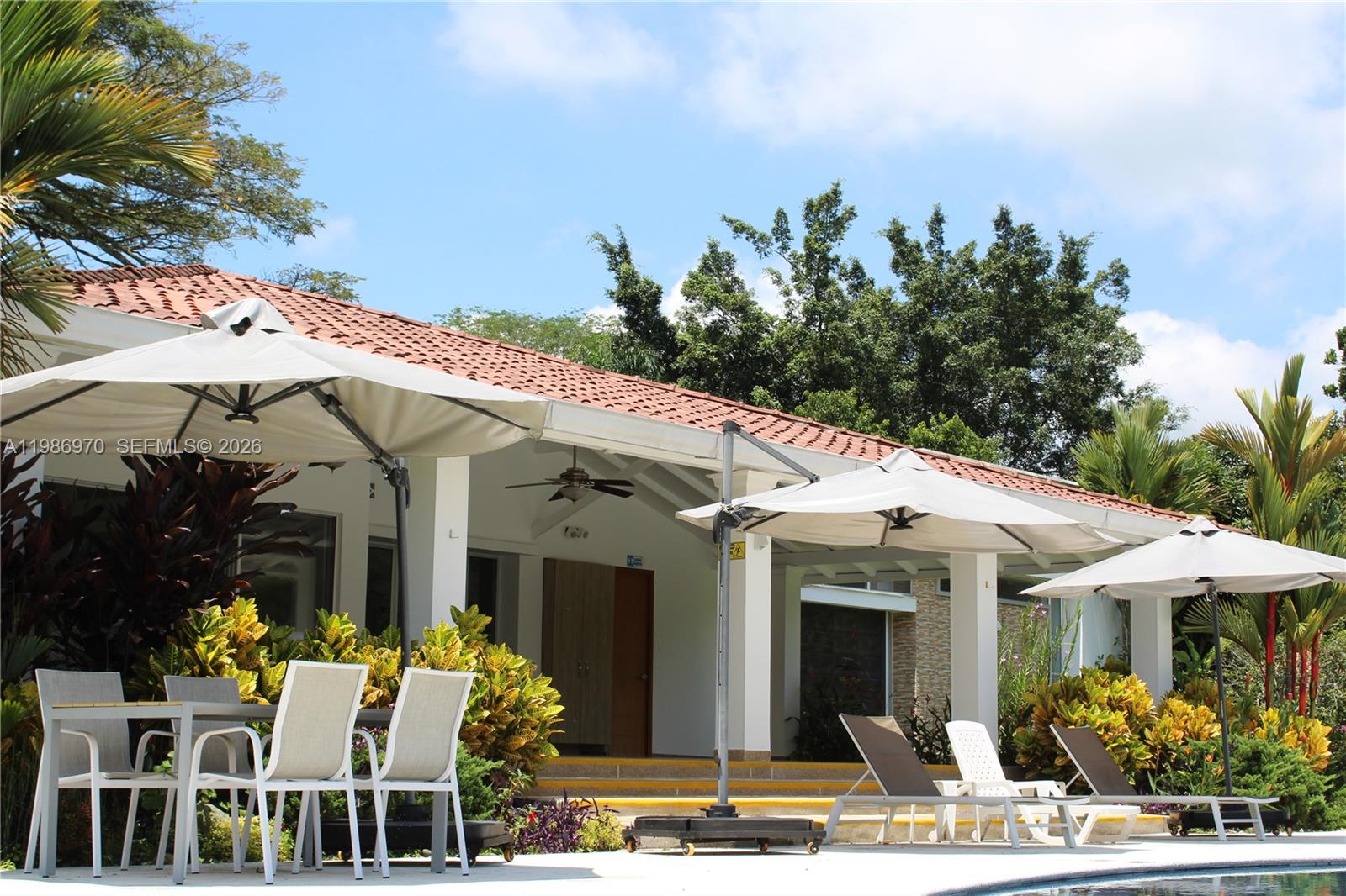A patio area features outdoor dining furniture, lounge chairs, umbrellas, and a tiled roof building — 00 N Outside of Country, FL