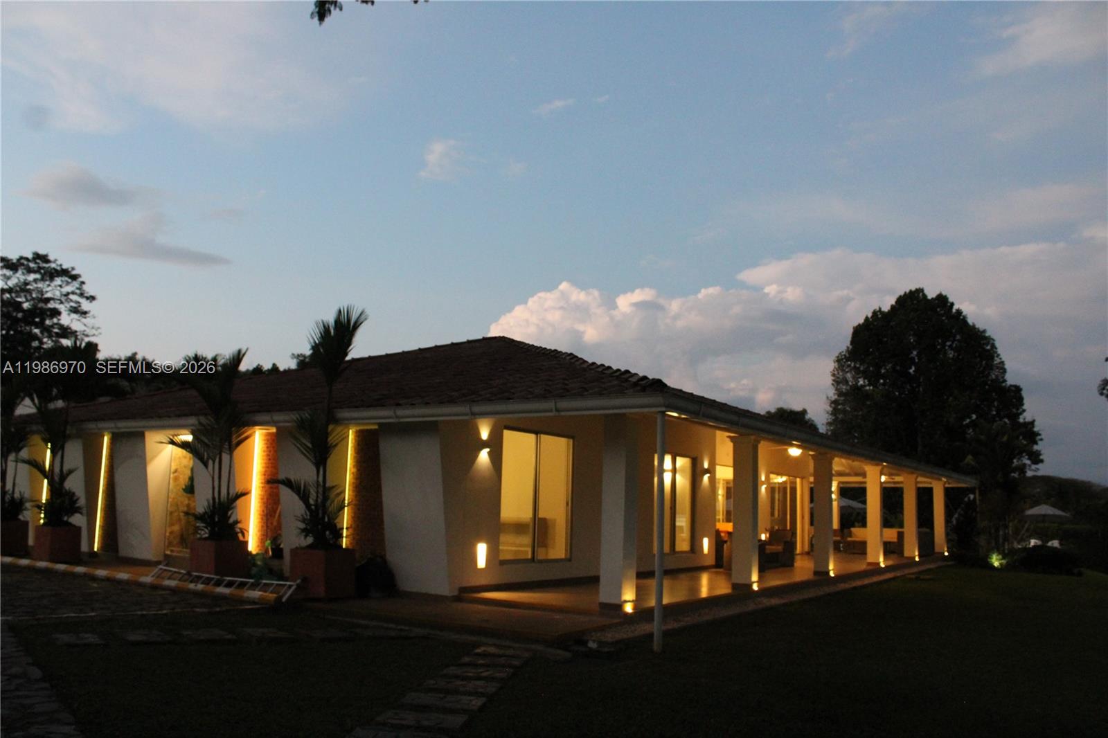A single-story house with a tiled roof and exterior lighting at dusk — 00 N Outside of Country, FL