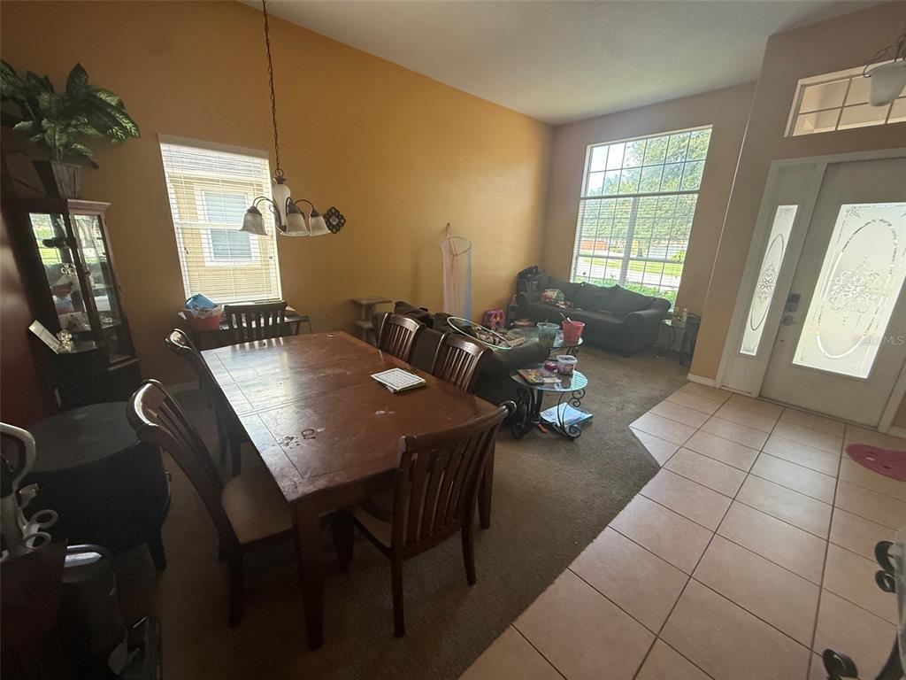 A dining area with a wooden table and chairs sits adjacent to a carpeted living room — 449 KAYS LANDING DRIVE, SANFORD, FL