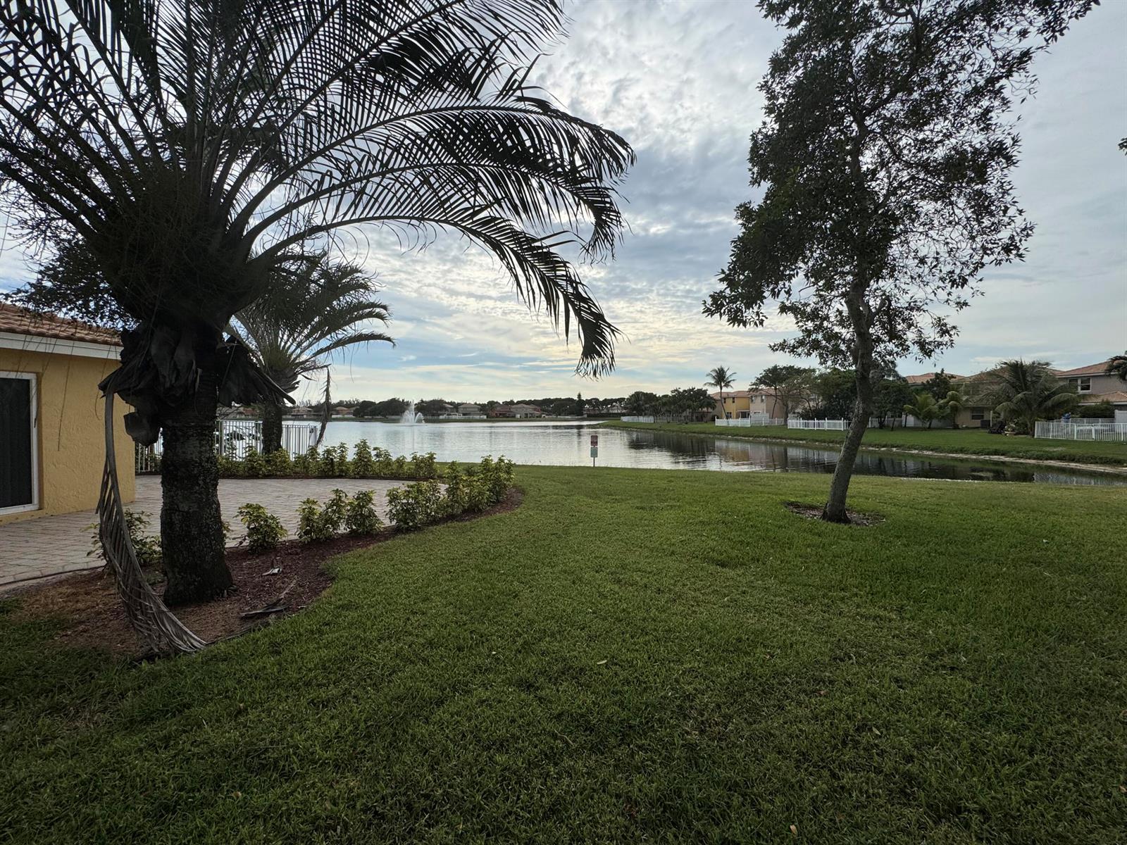 A view of a backyard lawn, a patio, a palm tree, and a lake — 3472 Commodore Court, West Palm Beach FL 33411, WEST PALM BEACH, FL
