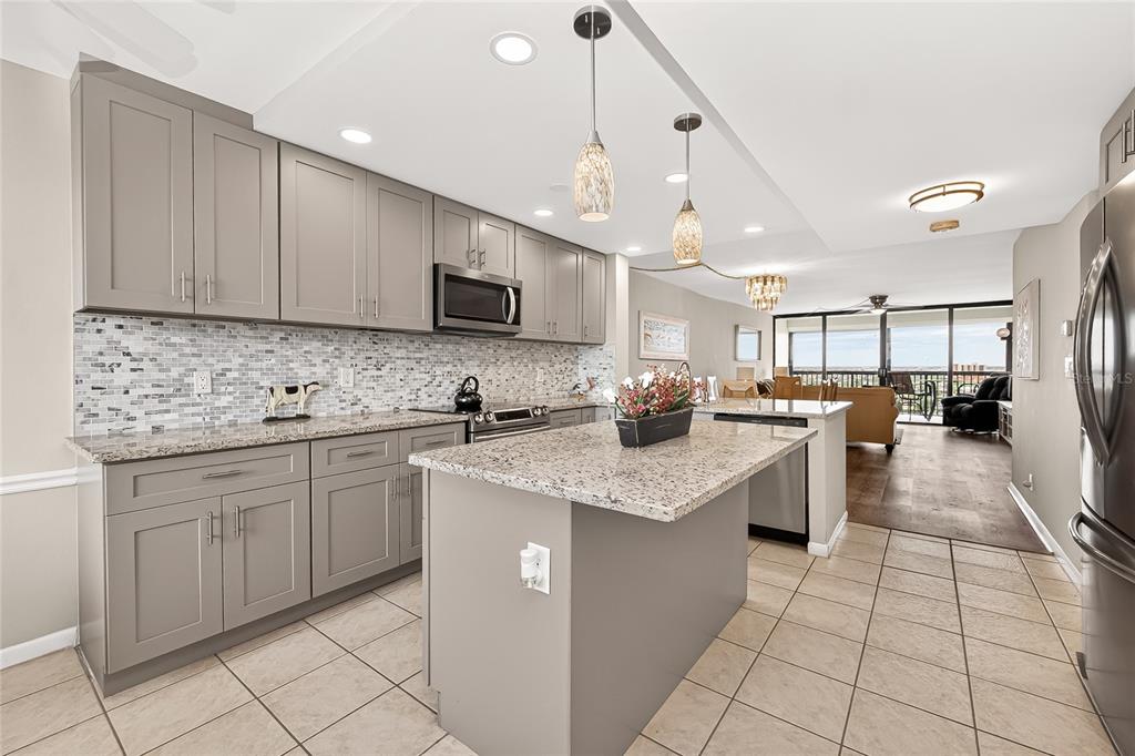 A kitchen with gray cabinets, granite countertops, a center island, and tile flooring — 9425 BLIND PASS ROAD UNIT 1103, ST PETE BEACH, FL