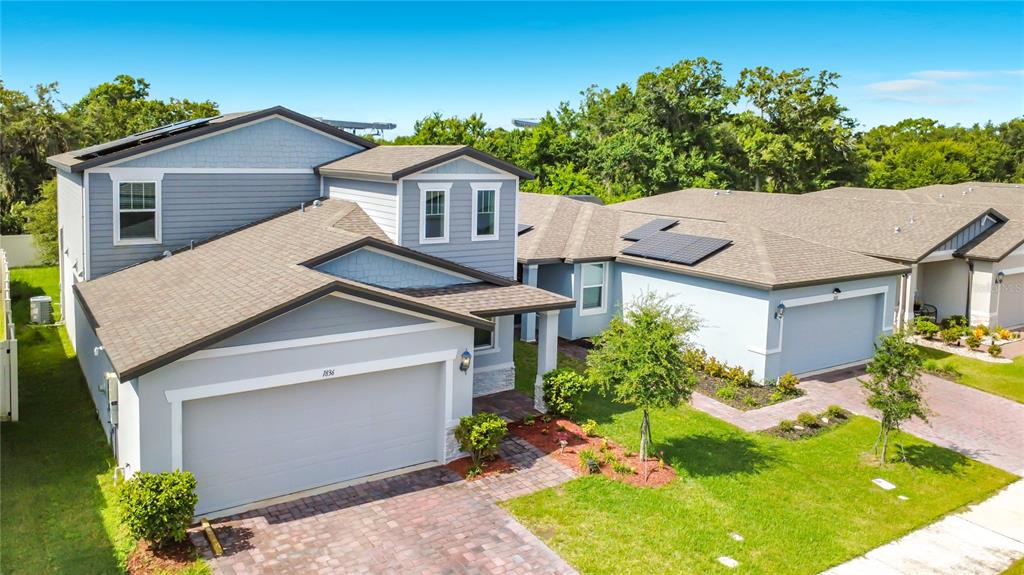 An aerial view of a two-story blue house with a garage and solar panels — 1836 CARNOSTIE ROAD, WINTER HAVEN, FL
