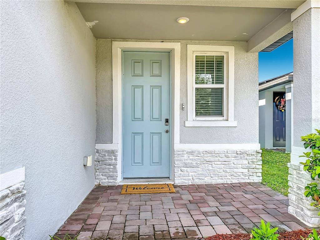 A light blue front door with a stone base sits on a brick porch — 1836 CARNOSTIE ROAD, WINTER HAVEN, FL