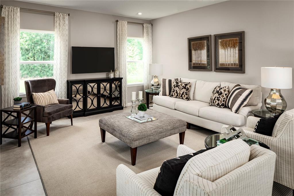 A living room features a white sofa, a gray ottoman, two armchairs, and a media console — 1039 OCEAN LODGE ROAD, LADY LAKE, FL