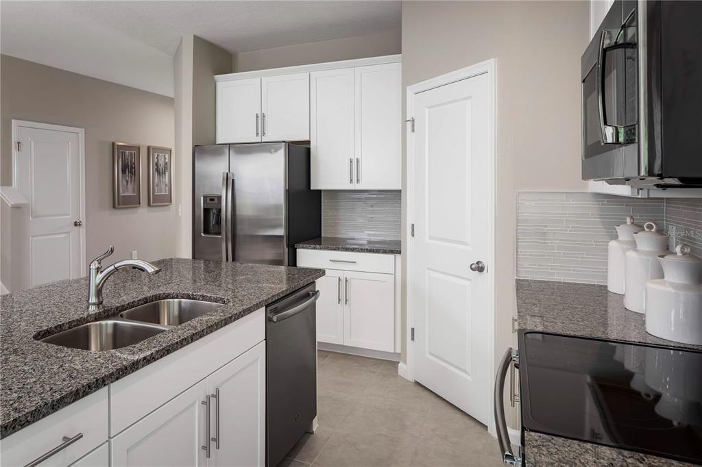 A kitchen features white cabinets, granite countertops, stainless steel appliances, and a double-basin sink — 1039 OCEAN LODGE ROAD, LADY LAKE, FL