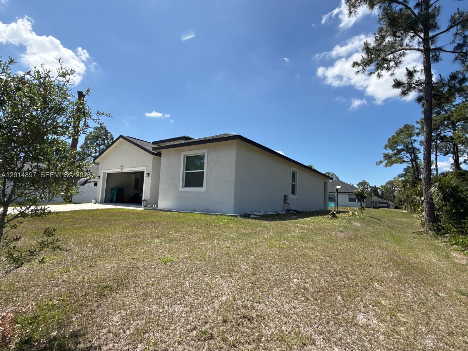A side view of a single-story house with a garage and a grassy yard — 5020 Myrtlewood RD, La Belle FL 33935, LA BELLE, FL