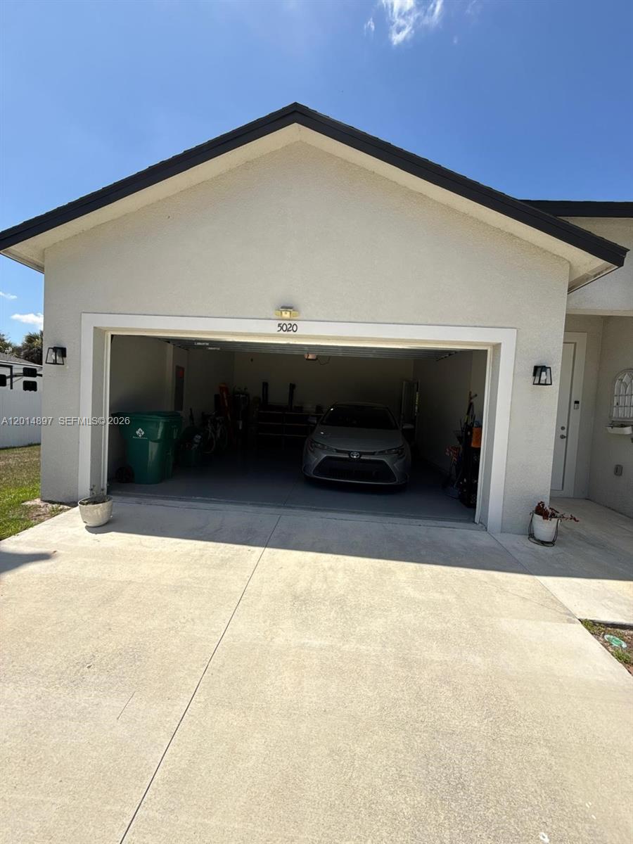 A single-car garage with a parked sedan is visible from the concrete driveway — 5020 Myrtlewood RD, La Belle FL 33935, LA BELLE, FL
